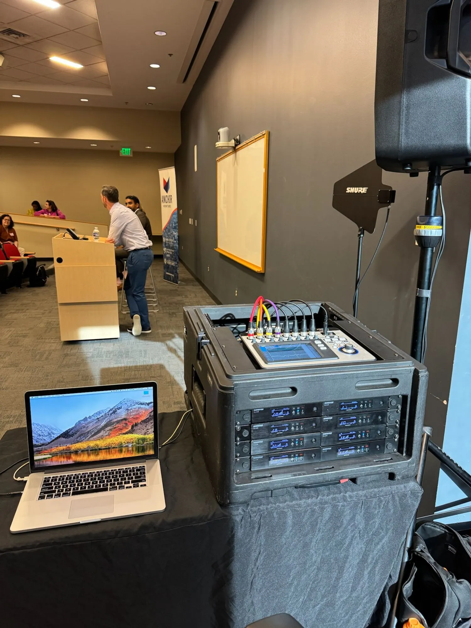 Compact digital console and racked Shure QLXD wireless receivers at the side of the lecture room