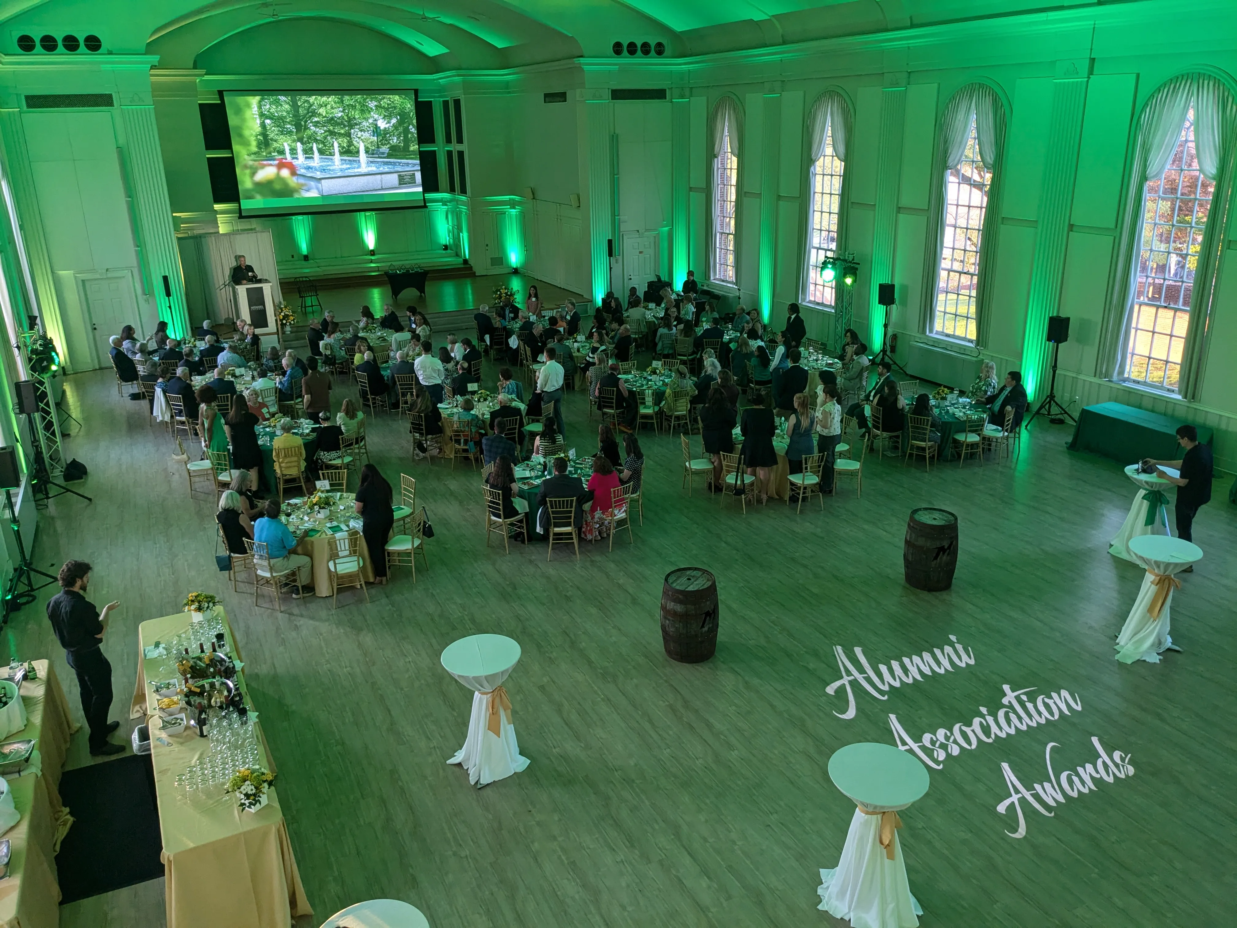 Historic college hall set for an alumni awards dinner — green uplighting on the columns and a custom gobo projected on the dance floor