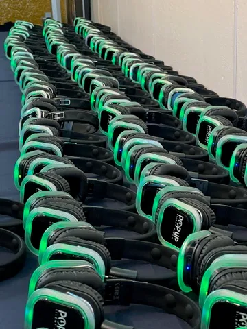 Rows of LED silent-disco headsets glowing green on a distribution table