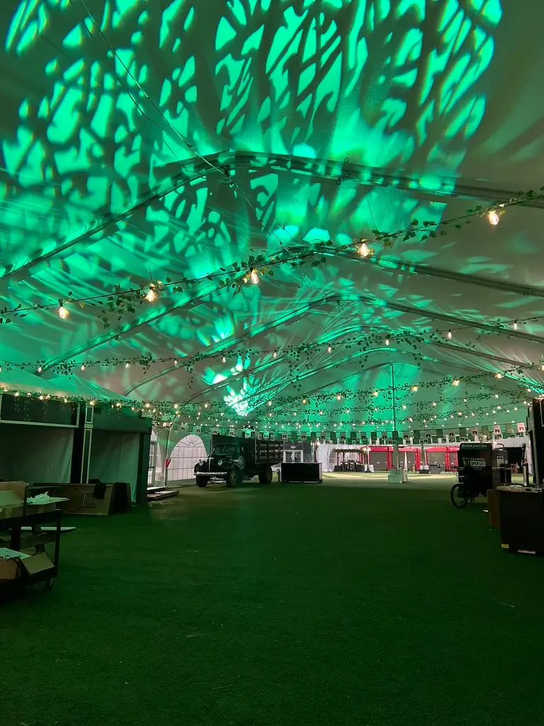 Event tent mid-build with a green leaf-pattern gobo wash across the ceiling and walls